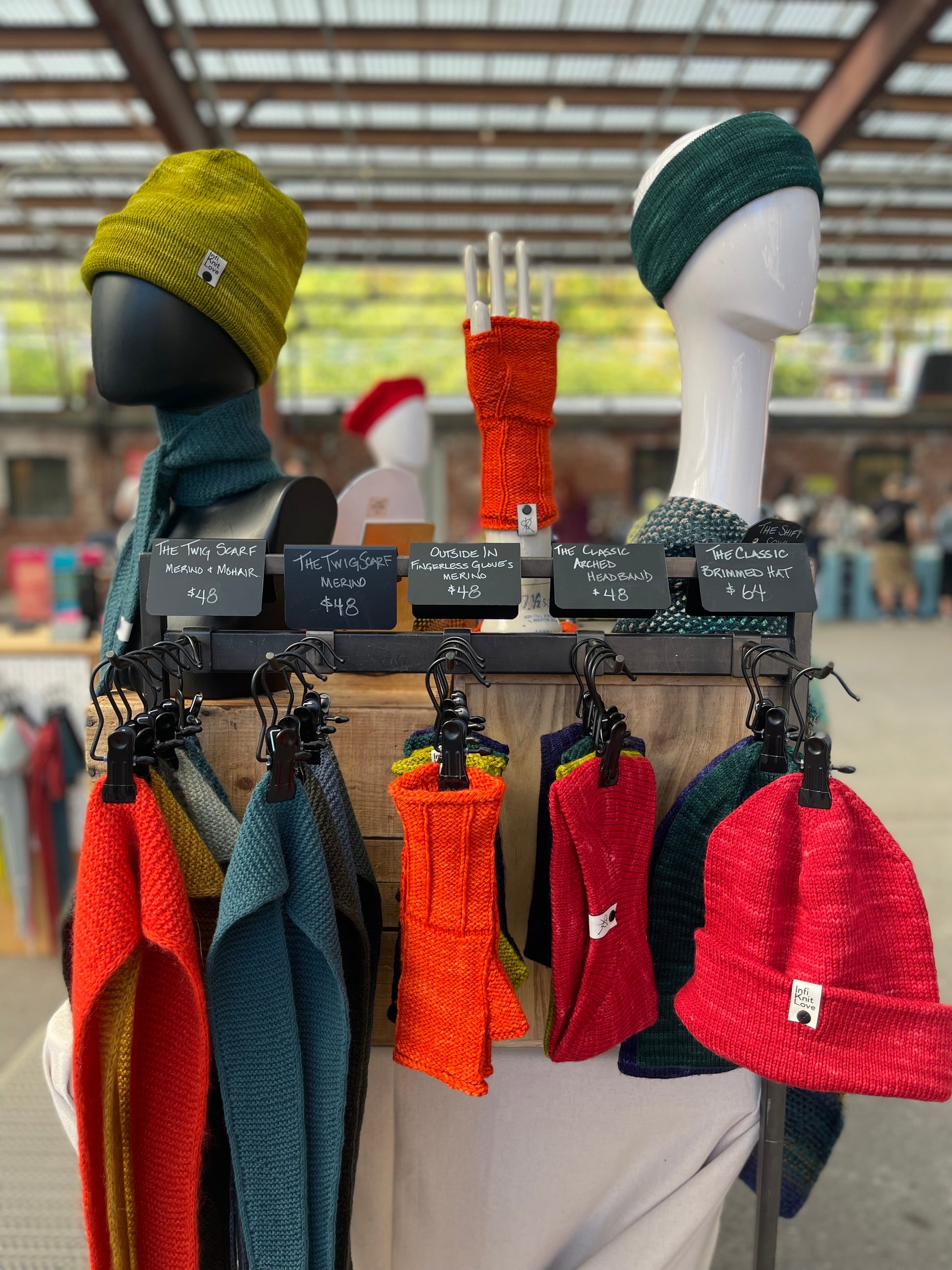 Market display of hats headbands fingerless gloves and scarves with a blurred indoor background